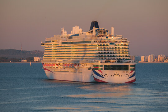 Massive gigantic modern cruiseship cruise ship liner Iona or Arvia in Cadiz, Spain during summer Mediterranean cruising with harbor and container port infrastructure