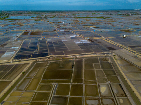 Aerial view of traditional salt fields, showcasing a vast geometric landscape of salt ponds and evaporation basins.