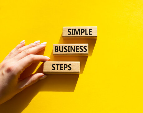 Concept words simple business steps on wooden blocks arranged as steps. Business planning concept. Businessman hand arranging wooden blocks. Yellow background. Copy space.