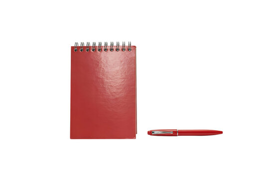 Shiny red spiral notebook standing upright next to a matching red ballpoint pen on a plain white surface isolated on a transparent background