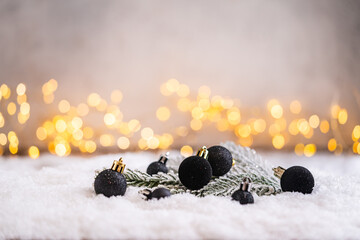 Naklejka premium A Christmas background featuring sleek black baubles and a curling black ribbon nestled in frosted pine on snow, softly lit by warm twinkling lights with copy space for modern designs.