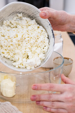 Cooking process. Healthy recipe. Female chef hand adding cottage cheese in bowl on kitchen counter preparing tasty dairy homemade meal.