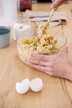 Bakery process. Mixing dough. Female chef hand stirring sweet mass with raisins oat flakes for healthy confectionery treat production.