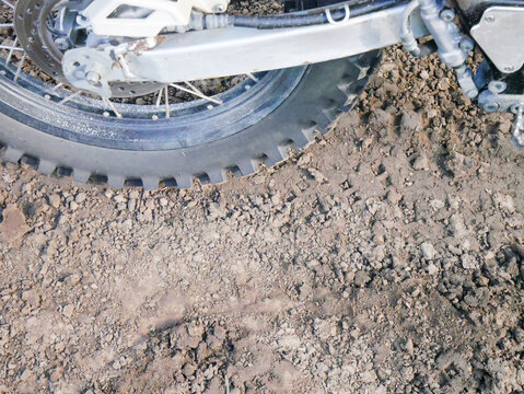 Motocross bike wheel and swingarm on rough muddy ground