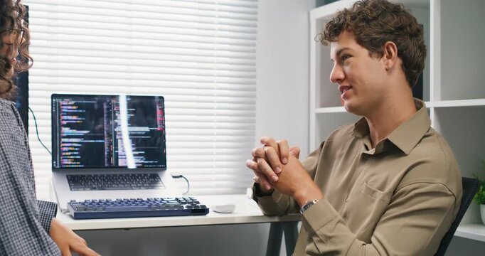 Caucasian and Latin engineers discuss architecture diagrams, code flows, and deployment strategy around a conference table with laptops and monitors.