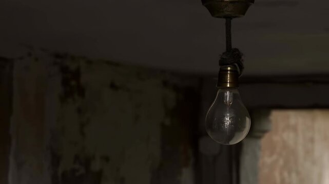 Hanging incandescent bulb switching between lit and unlit states inside rustic interior with peeling plaster walls, tarnished socket, cloth wrapped cord, warm glow, shadows, and worn texture