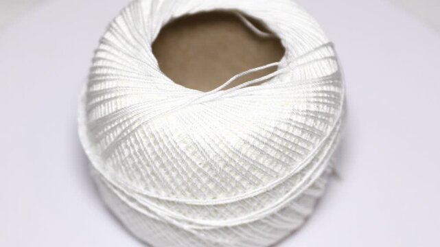 A ball of white yarn on a white surface. Rotating in a circle