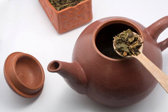 Close-up of a Traditional clay chinese teapot with a spoonful of loose leaf green tea leaves