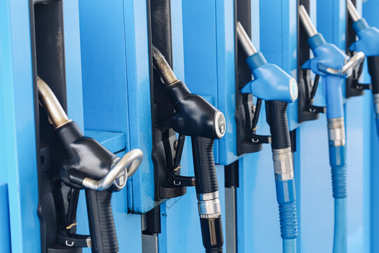 Fuel pump nozzles at station. Black and blue dispenser handles. Diesel and gasoline refueling equipment. Petroleum retail infrastructure for vehicles. Fuel sales form commercial energy background.