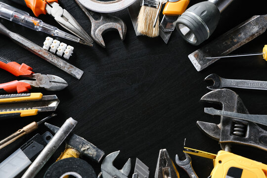 Assorted hand tools arranged around open center on black background