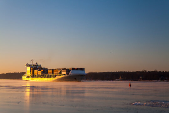Cargo ship sailing in the frozen Dane River at sunset, Klaipeda, Lithuania