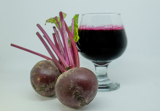 Close-up of a glass of fresh beetroot juice with two beetroots on a white background