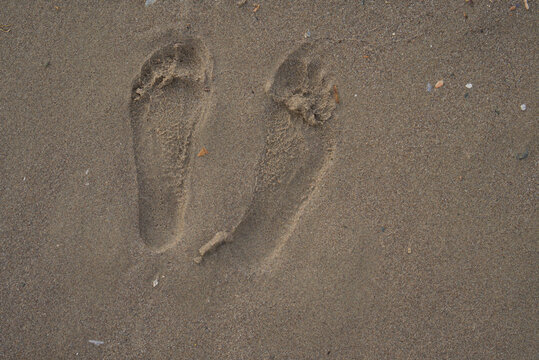 France, Valras Plage August 2026 &mdash; Pair of human footprints on wet sand beach background, summer travel vacation concept, feet marks, texture macro, copy space desktop wallpaper search background