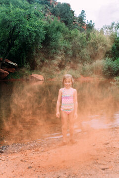 Little Girl Throwing Red Sand on Beach in Sedona