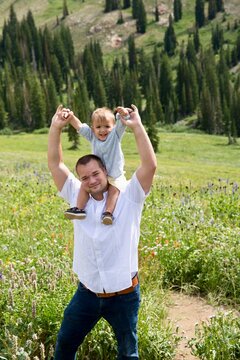 Portrait of a man standing in a field with his young son sitting on his shoulders, Albion Basin Meadow, Albion Basin, Little Cottonwood Canyon, Utah, USA