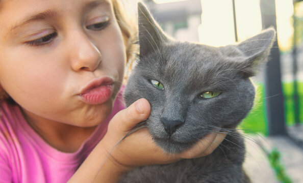 A child loves a cat outdoors. Selective focus.
