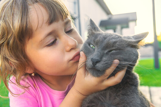 A child loves a cat outdoors. Selective focus.