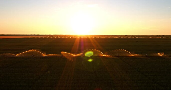 Aerial view of agricultural irrigation system watering field at sunset