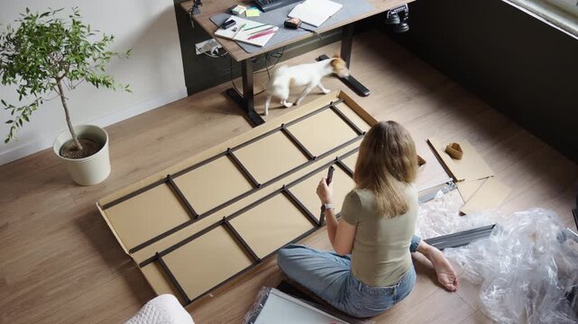 Woman assembling metal shelving frame on floor in home office