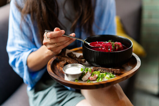 Close-up of a woman sitting on a cafe terrace eating a bowl of borscht soup on a summer day