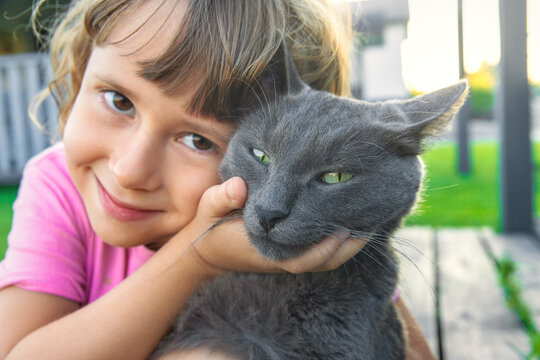A child loves a cat outdoors. Selective focus.