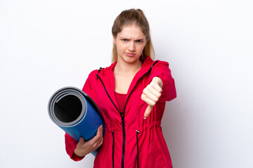 Teenager girl going to yoga classes while holding a mat isolated on white bakcground showing thumb down with negative expression © luismolinero
