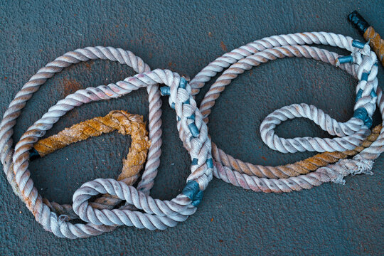 Old mooring ropes on concrete surface.