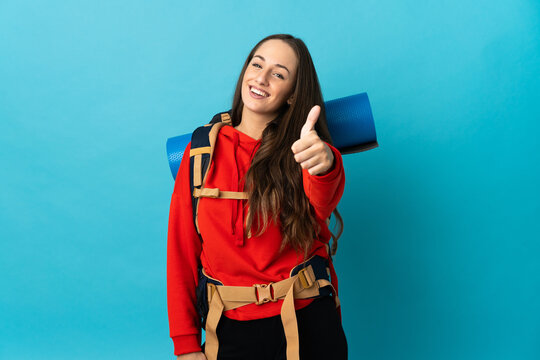 Mountaineer woman with a big backpack over isolated background with thumbs up because something good has happened