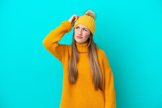 Young caucasian woman wearing winter jacket isolated on blue background having doubts and with confuse face expression