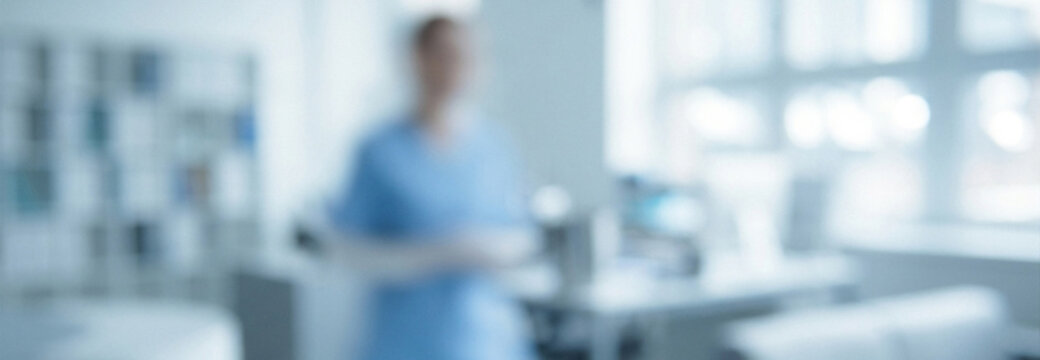 A blurred image of a medical professional in a healthcare environment, showcasing a modern hospital setting with medical equipment and bright lighting.