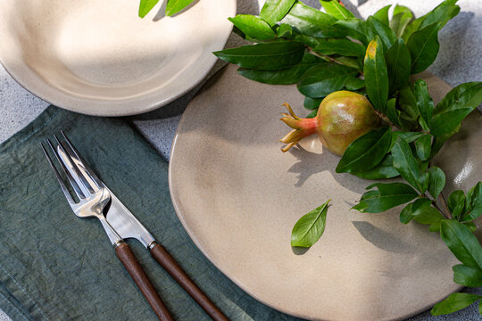 Close-up overhead view of an Autumnal place setting decorated with a fresh pomegranate branch