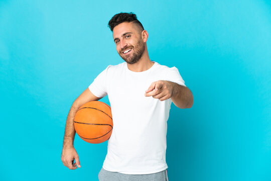 Caucasian man isolated on blue background playing basketball and pointing to the front