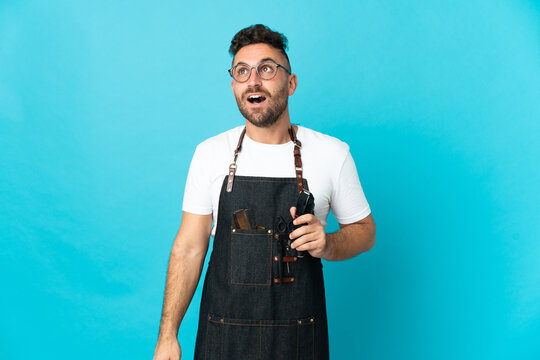 Barber man in an apron looking up and with surprised expression