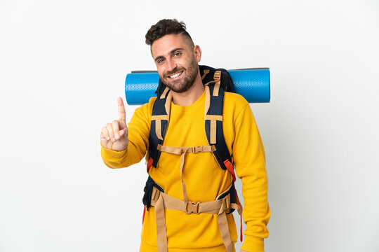 Young mountaineer man with a big backpack over isolated background showing and lifting a finger