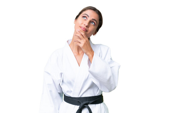 Young Uruguayan woman doing karate over isolated background looking up while smiling
