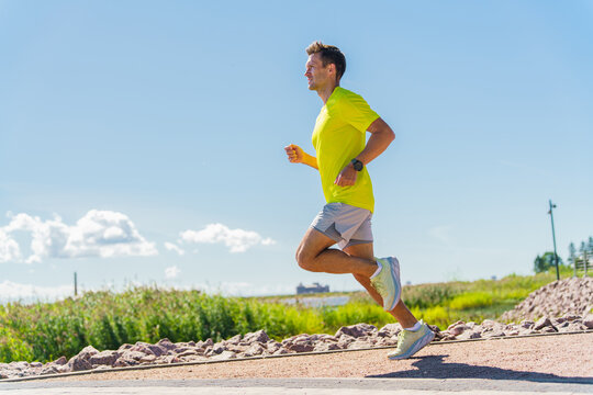 Jogger moves energetically along a sunny path next to lush greenery