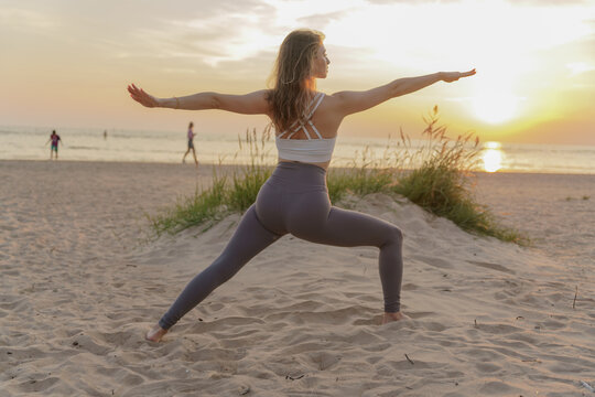 Graceful yoga practice at sunset on a serene beach with soft golden hues in the sky