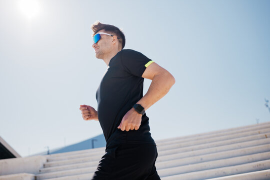 Running under the bright sun, a man embraces fitness and energy on the outdoor stairs