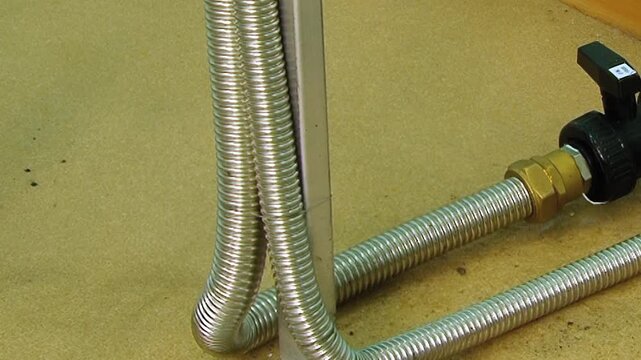 Flexible metal hoses securely attach to a sturdy valve and brass fitting, crafting a key section of an air filtration system.