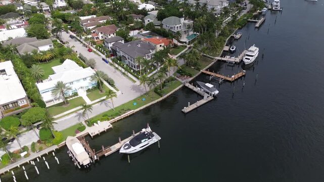 Smooth aerial drone shot flying sideways over an island neighborhood of private waterfront homes in Florida, showing a bay with moored boats, small private boat docks, house rooftops