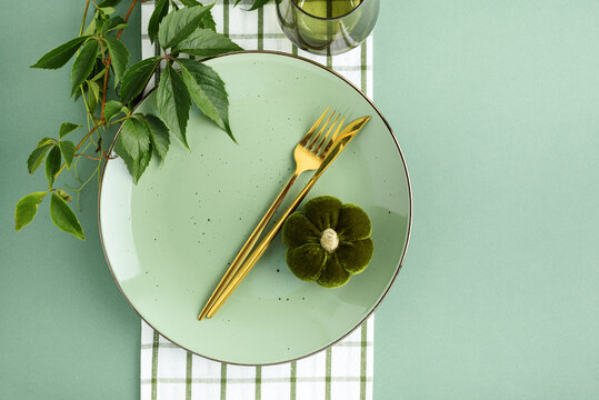Elegant Green Plate Setting with Golden Utensils and Velvet Flower Accent for Dining and Celebrations