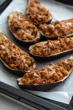 Several halves of stuffed eggplant baked with cheese on a baking sheet prepared for serving