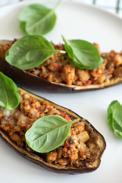 Two halves of baked stuffed eggplant topped with fresh basil leaves and melted cheese presentation