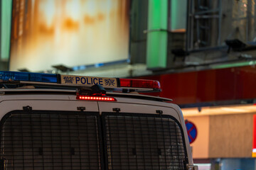 Close-up of emergency strobe lights and bilingual Police sign on the roof of an urban police patrol vehicle at night. © Sergej