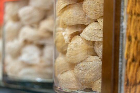Detailed view of high-grade dried swiftlet nests stacked in a cylindrical glass container in a Chinese medicine store.