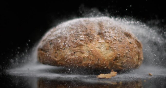 Slow motion of bread being dropped and creating dust and particles in the air