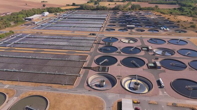 A drone orbit view of a huge waste water treatment plant in Minworth, UK focussing on the clarifier tanks and aeration lanes