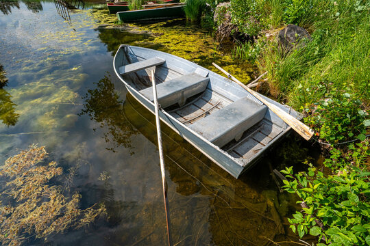 Kleine Metall-Ruderboot liegt im klaren Uferwasser eines Sees.
