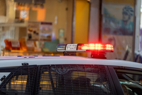 Close-up of an active red emergency lightbar with police lettering mounted on top of a marked law enforcement patrol vehicle at night.
