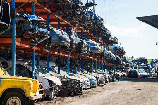 Stacked cars for used auto parts sale at an outdoor junkyard